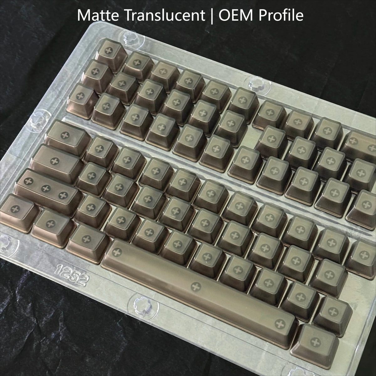 A close-up view of a profile of translucent keycaps for mechanical keyboards, showing rows of brown and clear plastic keys.