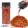 A glass jar of holographic chunky nail glitter mix with a shaker top next to a pile of the same orange-red glitter.