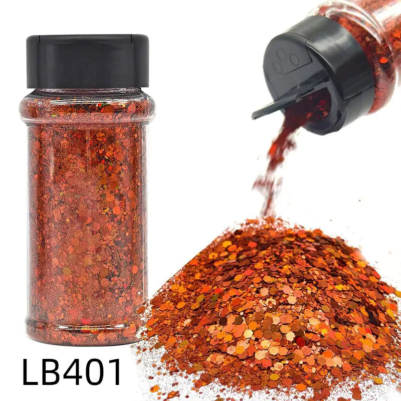 A glass jar of holographic chunky nail glitter mix with a shaker top next to a pile of the same orange-red glitter.