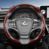 A black steering wheel with red carbon fiber texture accents and controls in a car interior.