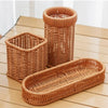 A set of handwoven wicker serving baskets in natural brown tones, including a tall cylindrical basket and a rectangular servi