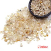 A pile of natural citrine crystal stone chips in various shades of yellow and amber.
