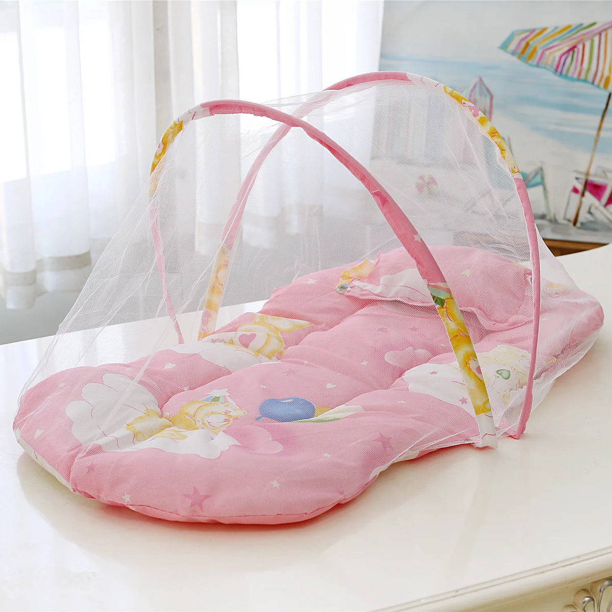 Pink foldable baby mosquito net with a mattress and pillow displayed on a white surface.