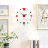 A round red and black analog wall clock with decorative framed artwork on a white wall.