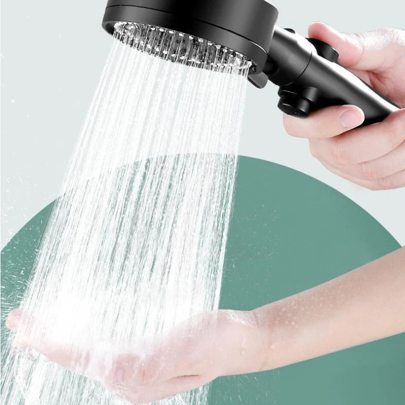 Eine Hand hält eine schwarze, verstellbare Duschkopf mit hohem Druck und spritzt einen starken Wasserstrahl auf eine Oberfläc