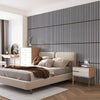 A modern bedroom featuring a bed with light gray linens against a dark vertical striped accent wall.