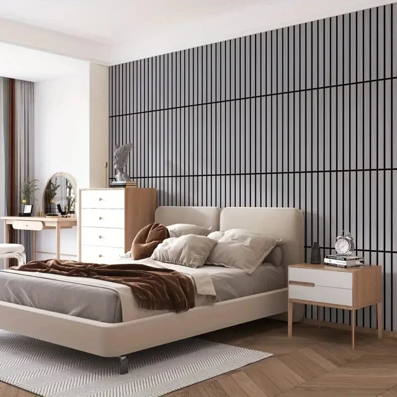 A modern bedroom featuring a bed with light gray linens against a dark vertical striped accent wall.