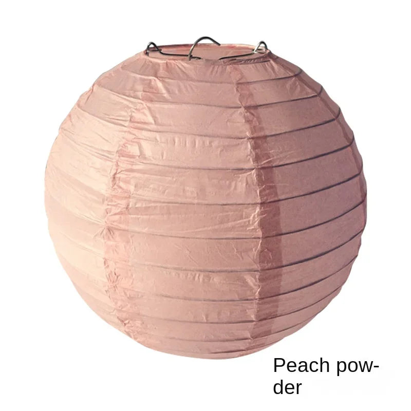 A round paper lantern in a soft peach powder color with vertical pleats.