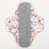 Reusable cotton menstrual pads with a pink floral pattern and a gray absorbent core.