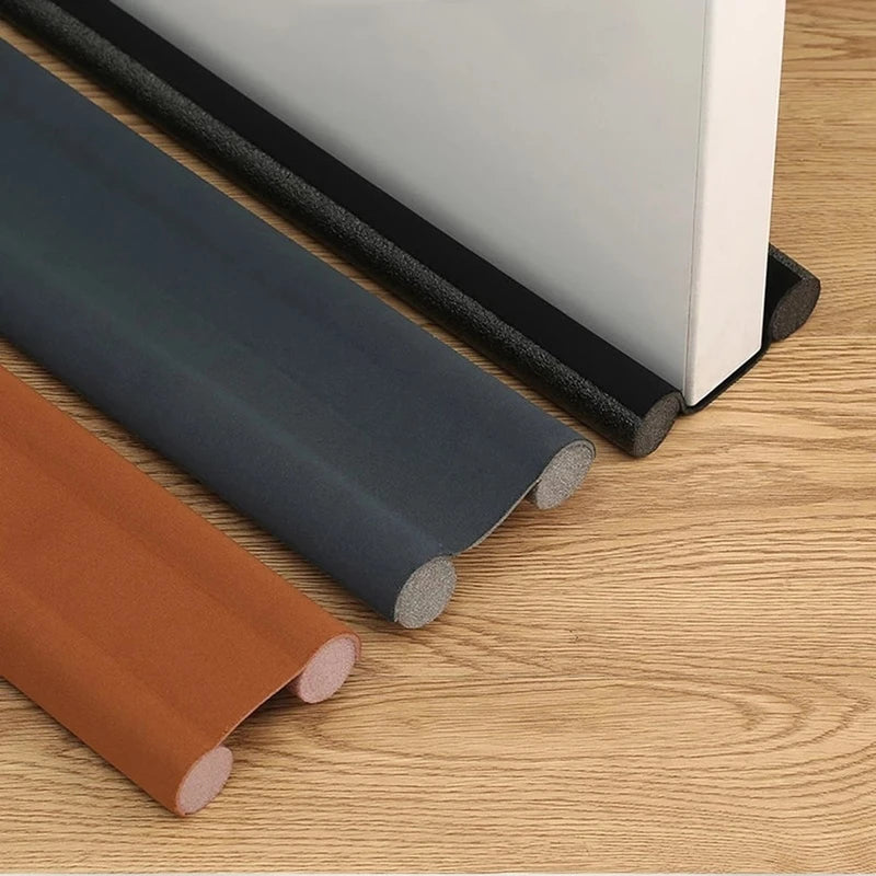Rolls of flexible weather stripping and a white door blocker are shown on a wooden surface.