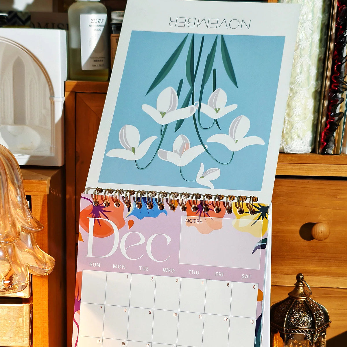 A desk calendar showing a November and December monthly planner with floral designs.