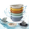 A stack of silicone animal finger puppet bath toys in various colors floating in water.