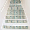 A staircase with white risers and treads featuring blue and gray wood grain peel and stick wallpaper.