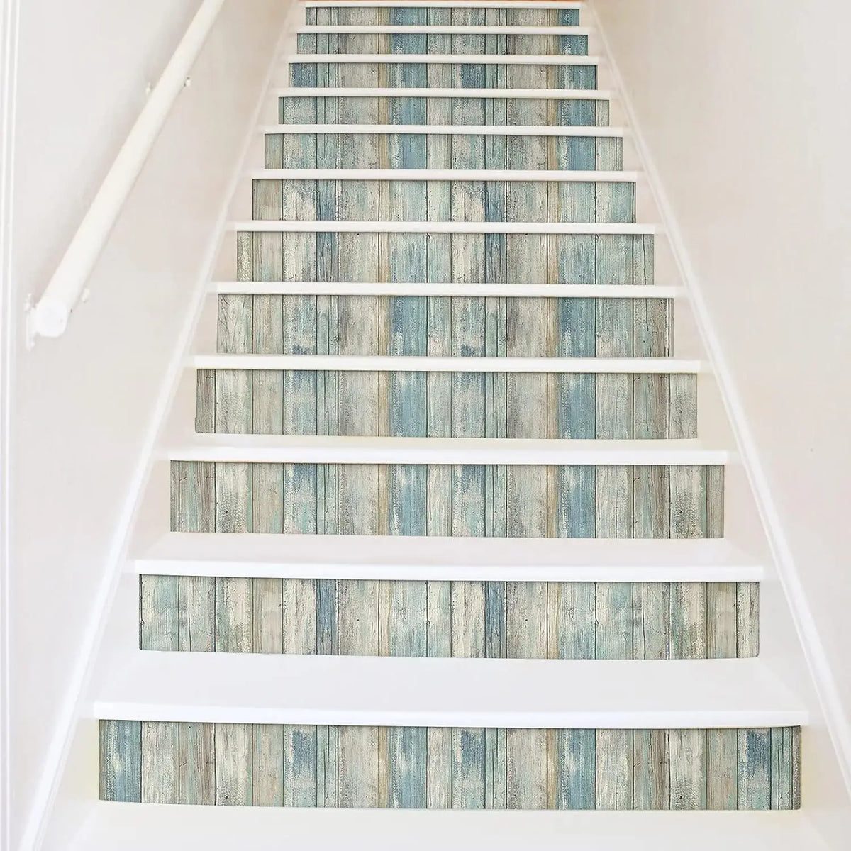 A staircase with white risers and treads featuring blue and gray wood grain peel and stick wallpaper.