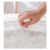 A hand gently touches the fluffy white fibers of an extra large Nordic fur rug.