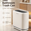 A white slim touchless trash can with a lid is shown on a marble countertop in a bathroom setting.