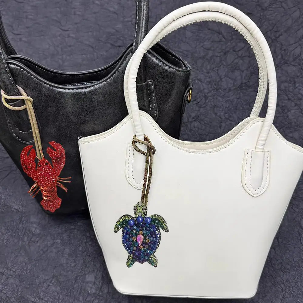 White leather handbag with a gold strap and a colorful rhinestone octopus and turtle pendant charm
