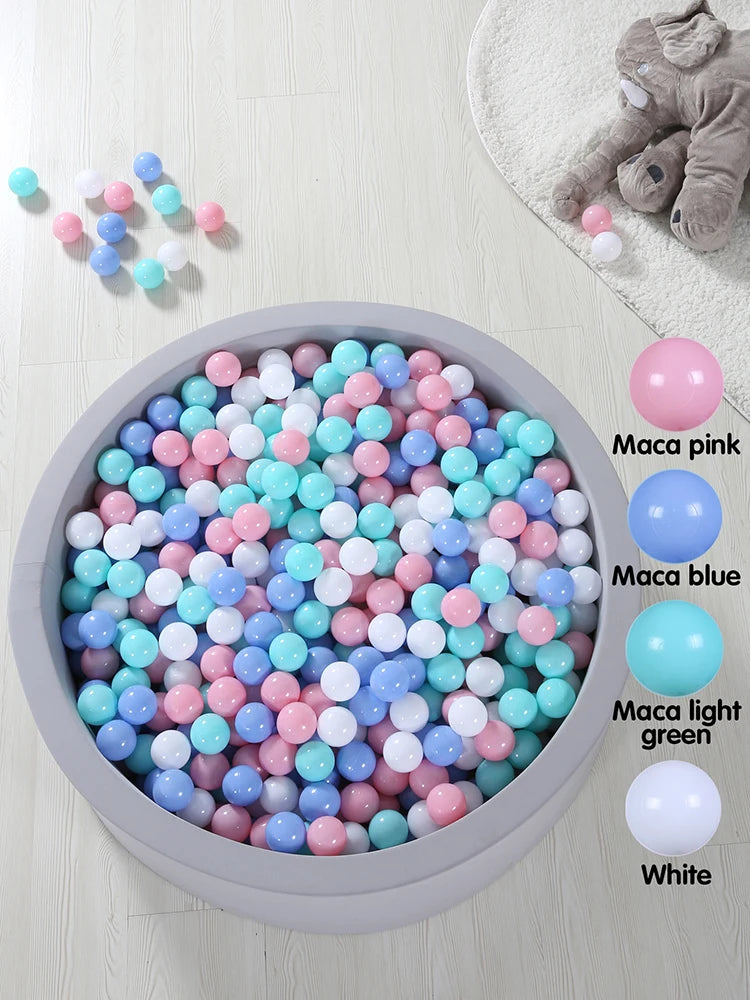 A collection of colorful, crush-proof ball pit balls in pink, blue, and white are displayed in a gray bowl.
