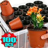 A hand holds a terracotta seedling pot next to a stack of black and orange reusable plastic pots for gardening.