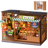 A wooden model kit of a vintage Japanese corner shop with an open display and a book nook insert.