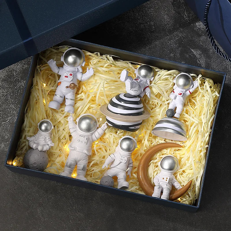 A collection of handcrafted astronaut figurine resin spacemen desk decor arranged in a box.