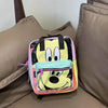 A yellow and black cow print backpack with pink trim resting on a beige sofa cushion.