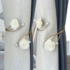 Elegant rose pattern curtain tiebacks with adjustable metal buckles on light gray and dark blue curtains.