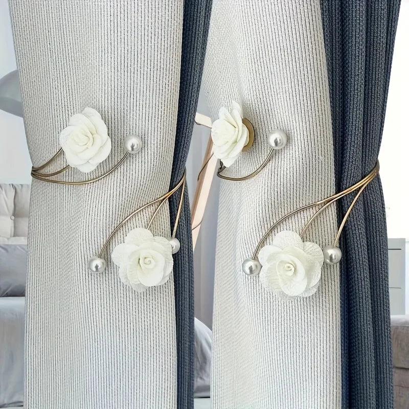 Elegant rose pattern curtain tiebacks with adjustable metal buckles on light gray and dark blue curtains.