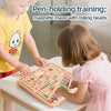 A young girl is playing a magnetic maze with rolling beads on a wooden board with a boy nearby.