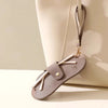 A light taupe glasses case with a retro lychee pattern PU leather design is shown resting on a cream-colored bag.