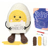 A crocheted yellow animal figure with black eyes and a sign reading PARKLIFE sits on a yellow surface.