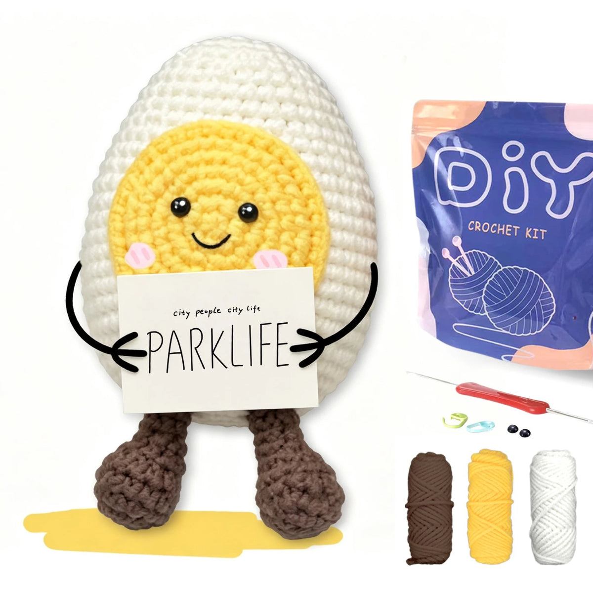 A crocheted yellow animal figure with black eyes and a sign reading PARKLIFE sits on a yellow surface.