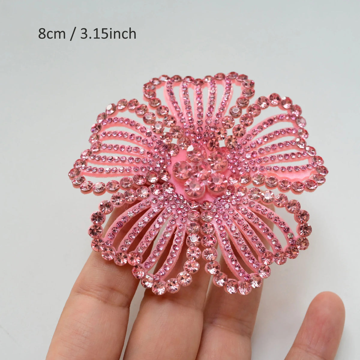 A close-up of a pink crystal rhinestone flower sew-on patch for clothing and accessories.