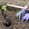 A hand wearing a purple glove is using a garden auger to create a hole in the soil for planting.
