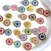 A collection of multicolor sew-on flower rhinestones in various shades of pink, blue, and gold arranged on a white surface.