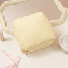A pale yellow, ribbed storage pouch with a zipper is displayed on a white surface, framed by a light-colored object.