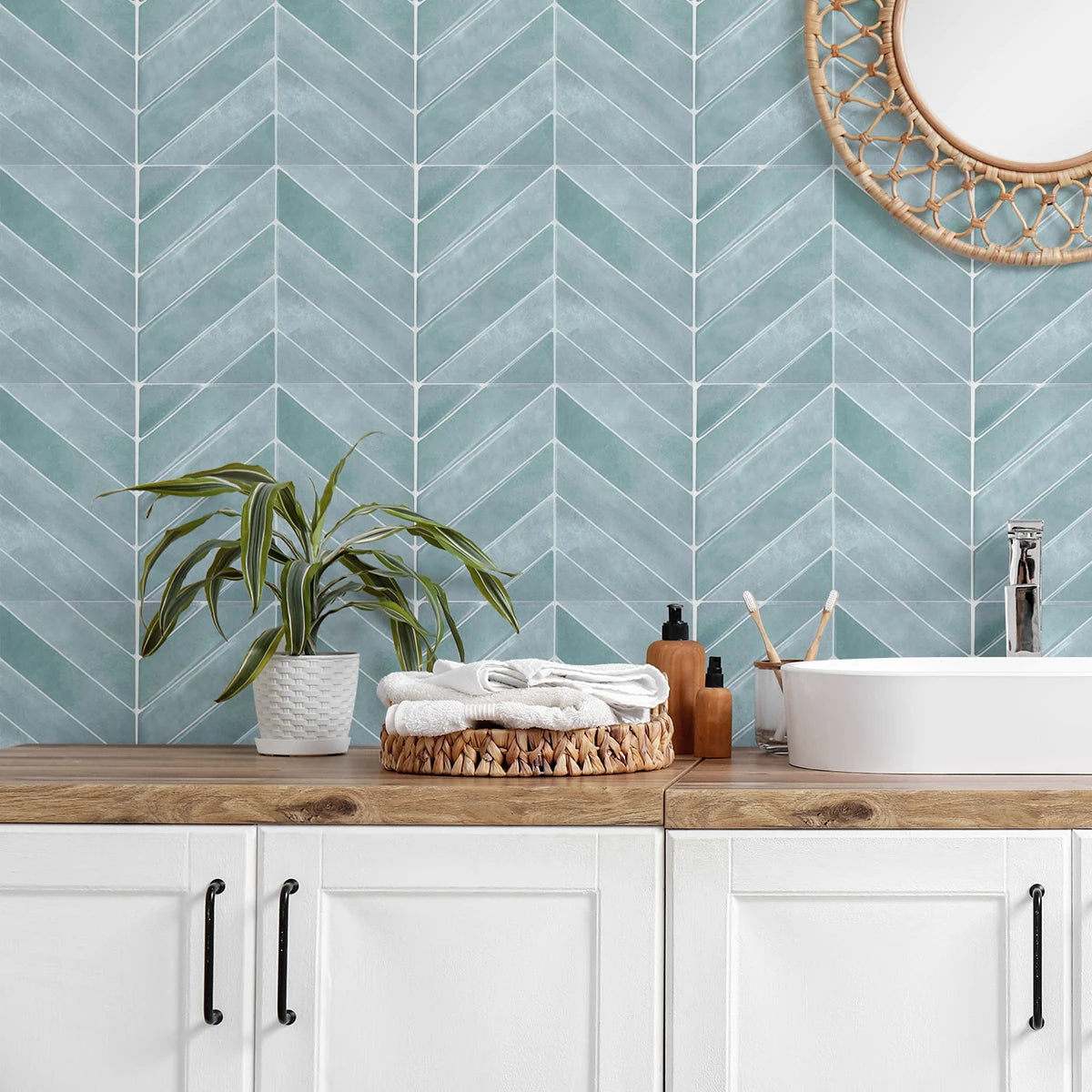 A bathroom vanity featuring a teal geometric tile wall, a potted plant, and a white sink.