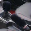 A close-up view of a plush black car gear shift and handbrake cover set inside a vehicle cabin.