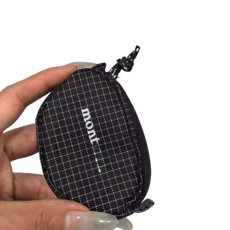 Une main tient un étui de casque en nylon à carreaux noirs et une pochette à cordon.