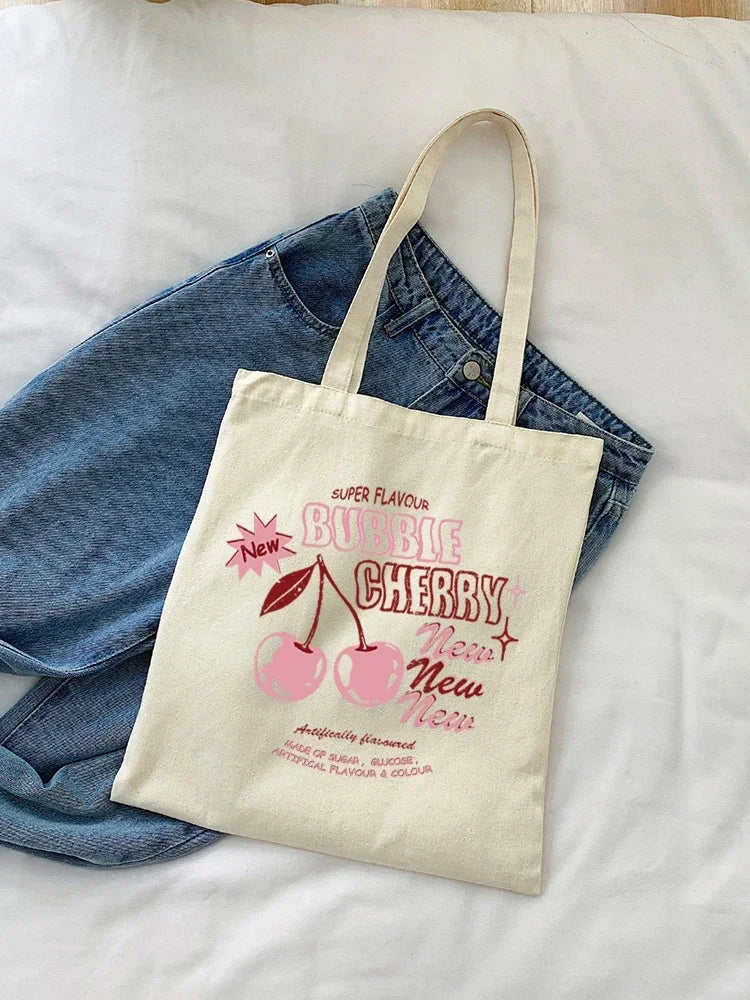 A canvas tote bag with a pink cherry print featuring the text Super Flavour Bubble Cherry New New