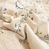 Light beige fabric with a subtle floral and animal pattern, folded to show texture.