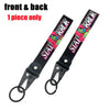 Front and back view of a black strap keychain featuring a pink and green anime girl design with a steel clip.