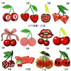 A collection of twelve embroidered iron-on patches featuring various fruit designs like cherries, apples, and berries.