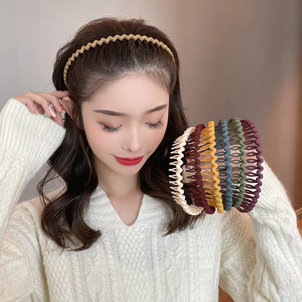 Eine Frau modelliert elegante, einfarbige Wellen-Haarbänder in ihrem dunklen Haar bei einem weißen Pullover.