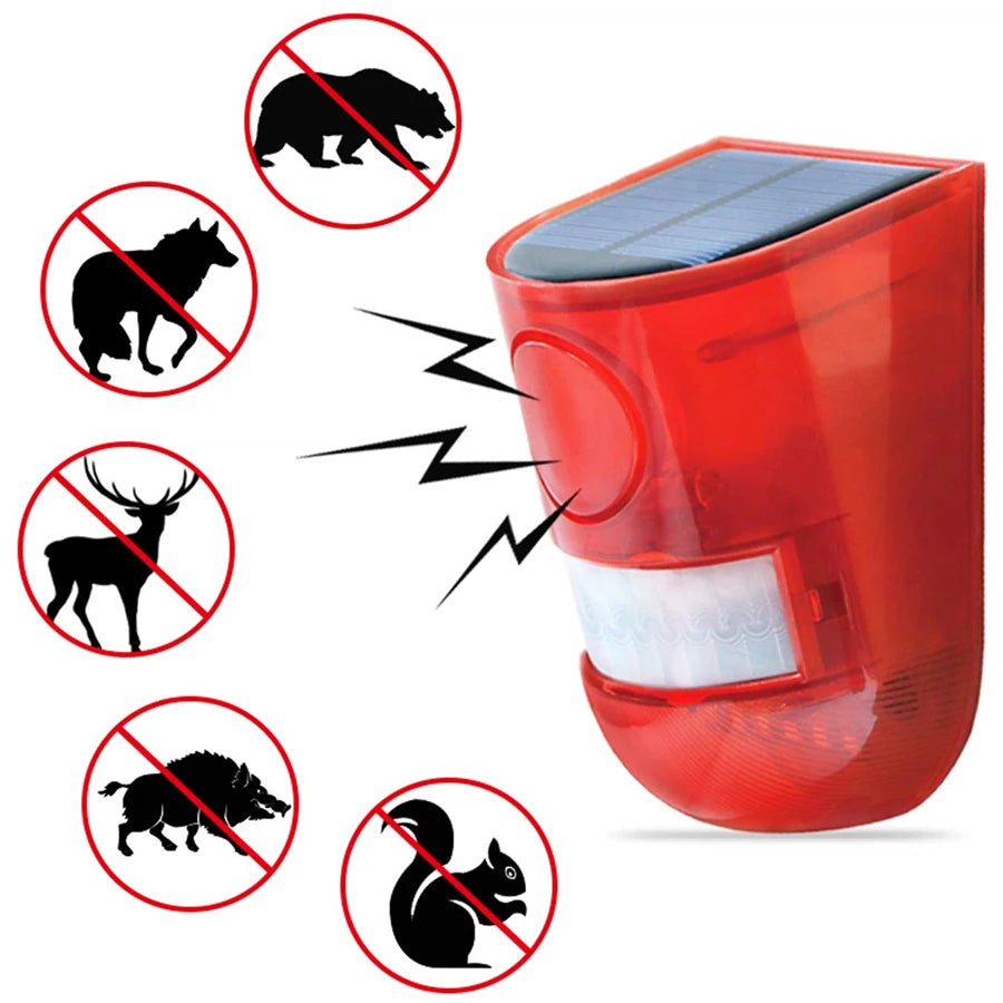 A red solar-powered motion sensor alarm device with a strobe light, surrounded by silhouettes of various animals.