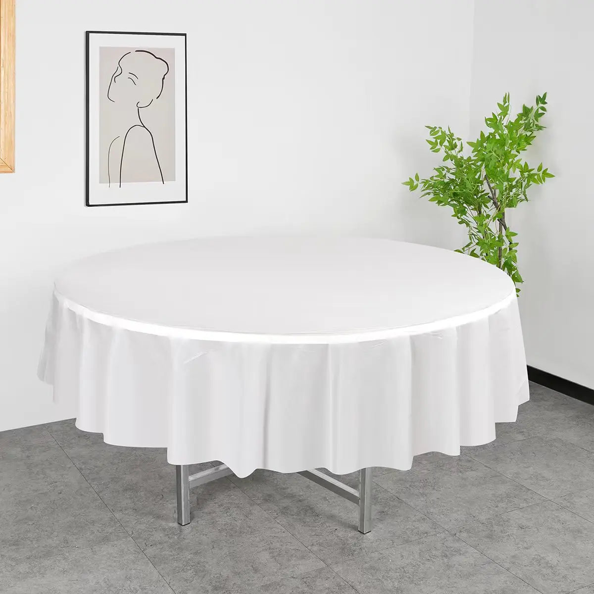 A white disposable round tablecloth is displayed on a table in a well-lit room.