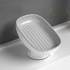 A white bathroom soap rack with a drain tray and suction cup, shown in a side view.