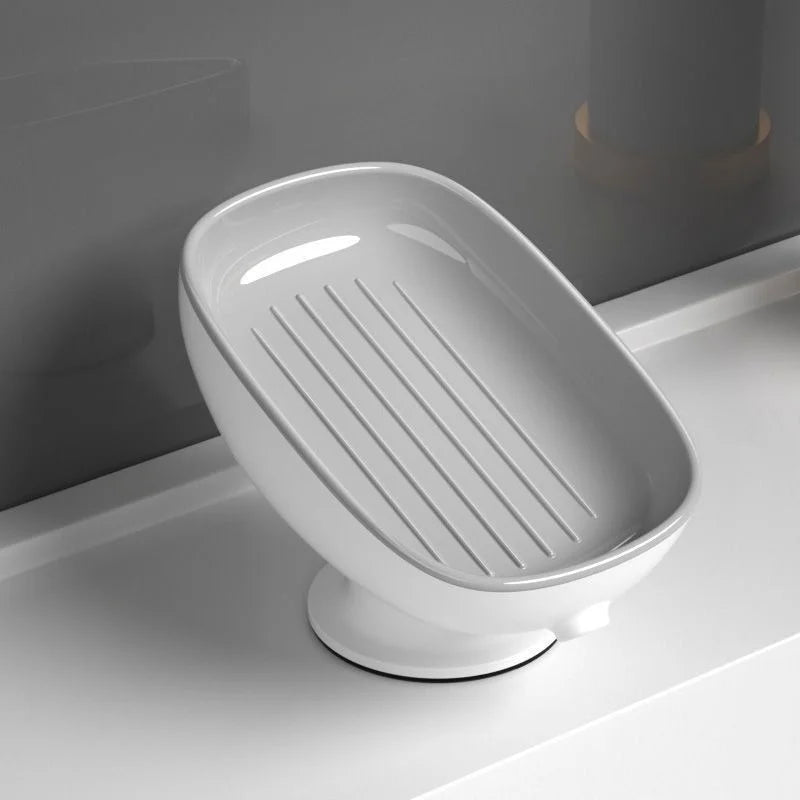 A white bathroom soap rack with a drain tray and suction cup, shown in a side view.