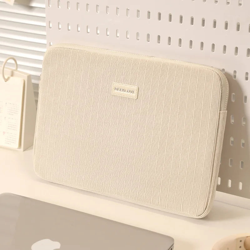 Una funda protectora delgada beige para laptop, mostrada sobre fondo blanco.