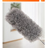 A close-up view of a fluffy gray microfiber duster with an extendable handle.